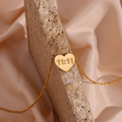 The durable 18k gold plated 11:11 necklace made from 316L stainless steel, resting on a textured natural stone.